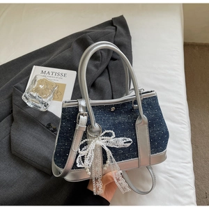 Detail of blue denim bucket bag with pearl lace bow and silver handle on bed