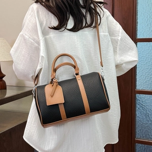 Close-up of a retro black and brown leather Boston bag worn by a model in a room