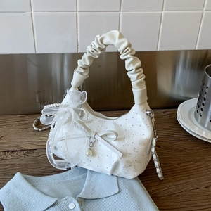 Detail of white quilted half-moon bag featuring pearl bow and ruffled cloud handle