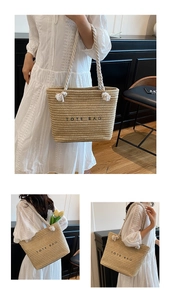 Detail of the woven straw tote bag featuring white rope handles and black tote bag text