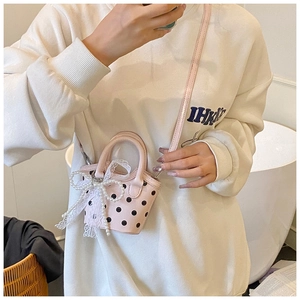 Detail of pink polka dot mini bag with white lace bow and elegant pearl strap charm