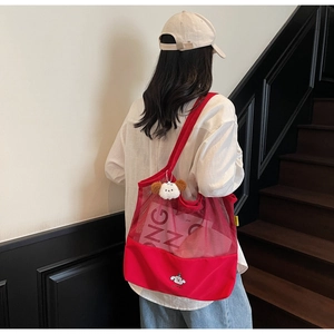 Detail of red mesh tote bag with white puppy embroidery and plush charm accessory