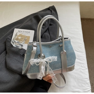 Detail of blue denim bucket bag with silver sequins, lace bow, and pearl fringe accents