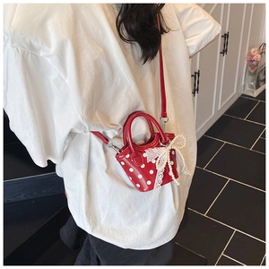 Detailed shot of red polka dot mini bag featuring lace bow and pearl charm accents