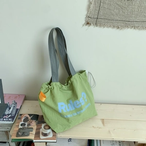 Detailansicht der großen grünen Canvas-Tasche mit Kordelzug und blauem Slogan-Aufdruck