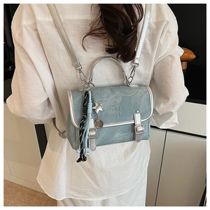 Detail of light blue denim mini backpack with silver metal buckles and chain straps