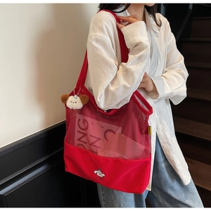 Detail of red mesh tote bag with white puppy embroidery and matching plush charm