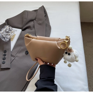 Close-up of khaki leather handbag featuring pleated design and white plush charm
