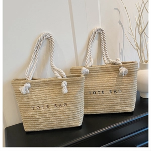 Detail of hand-woven straw tote bag with rope handles and bold tote bag lettering