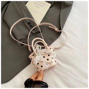Close-up of pink polka dot mini handbag with pearl chain, lace bow and adjustable strap