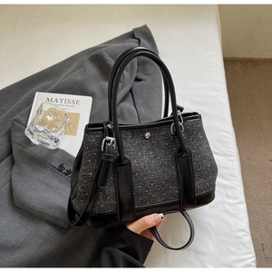 Detail of black tweed bucket bag with white polka dots and stylish leather handle