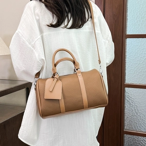 Detail of brown lychee-pattern leather boston bag with top handles and adjustable strap