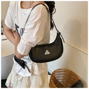 Detail of black wrinkled leather crescent bag with triangle silver metal clasp on model