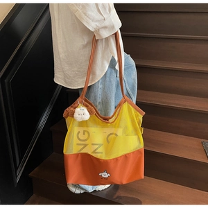Close-up of yellow mesh and orange canvas tote bag with cute dog pendant and printed logo