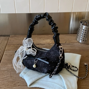 Close-up of black jacquard handbag featuring lace bows, pearls and a silver metal chain strap