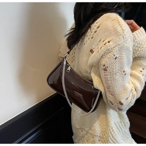 Détail du sac bandoulière en cuir verni marron foncé avec chaîne argentée sur modèle