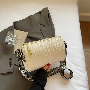 Close-up of woven cream bucket bag with jacquard strap and gold lock charm detail