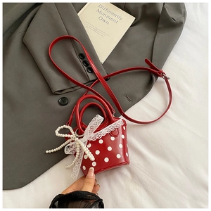 Close-up of red polka dot mini bag with white lace and pearl bows on suit fabric