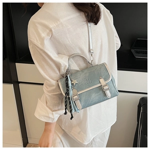 Detail view of light blue leather handbag showing twin metal buckles and star pendant
