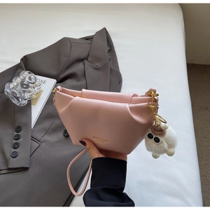 Detail of pink leather handbag with unique ruching and a white plush toy charm