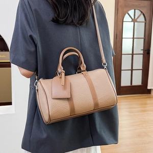 Chic camel leather Boston bag shown cross-body style on model with a textured finish
