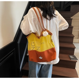 Detail view of contrast mesh tote bag with orange canvas and plush dog charm accessory