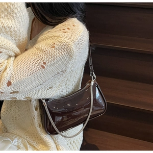 Détail d'un sac en cuir verni café brillant avec décoration de chaîne argentée