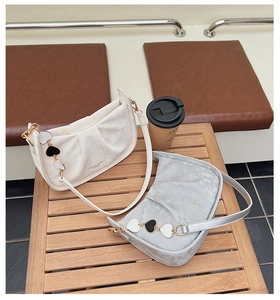 Détail de sacs croissants plissés blanc et gris avec pendentif coeur sur table en bois