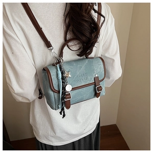Detail view of denim texture backpack with brown leather trim and metal star charms