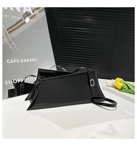 Detailed close-up of a black glossy patent leather shoulder bag with metallic buckle