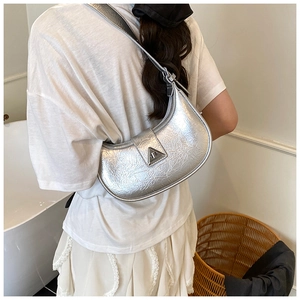 Detail shot of silver metallic crescent bag with pleated texture and triangular metal buckle