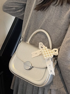 Sac bandoulière argenté métallisé avec nœud en perles et texture plissée sur mannequin