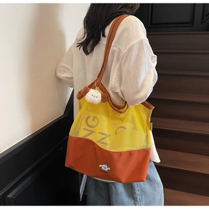 Detail view of contrast mesh tote bag with cartoon dog print and plush keychain charm