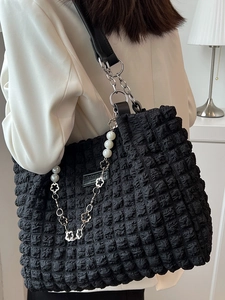 Black textured bubble tote bag with silver chain and pearl charms worn by a model