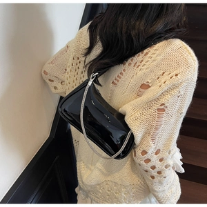 Détail du sac à bandoulière en cuir verni noir minimaliste avec fine chaîne argentée