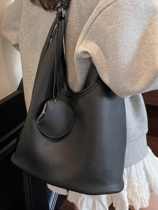 Minimalist black lychee pattern leather bucket bag with wide strap and round coin purse accessory