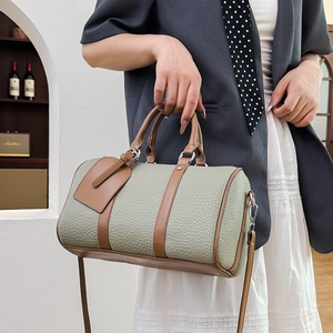 Detail of gray-green pebbled leather Boston bag with brown trim and silver hardware