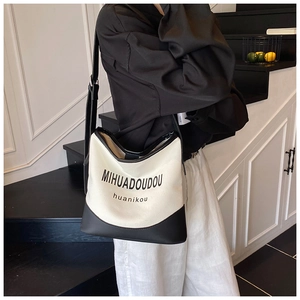 Detail of canvas bucket bag with black leather trim and elegant logo printing