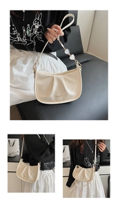 Détail du sac hobo plissé blanc avec pendentif cœur et accents de chaîne en métal