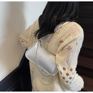 Détail d'un sac à bandoulière argenté métallisé avec chaîne porté à l'épaule par un mannequin