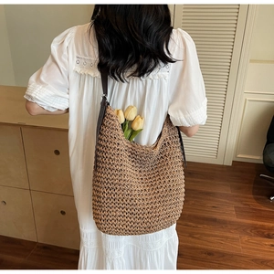 Détail du sac hobo en paille tressé à la main avec bandoulière en cuir marron foncé