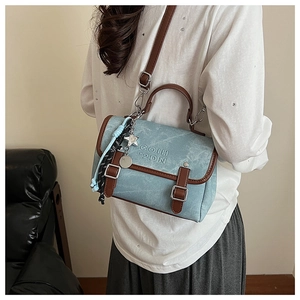 Detail view of sky blue vintage crossbody bag with brown straps and star charm