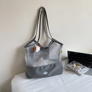 Detail of grey mesh tote bag with cartoon dog embroidery and plush keychain accessory