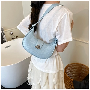 Detail of light blue crescent bag featuring pleated leather texture and metal buckle