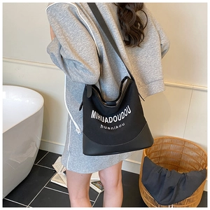 Detailed view of black canvas and leather crossbody tote bag in a lifestyle setting