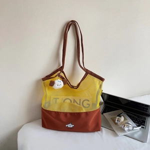 Detail of color-block mesh tote bag featuring cartoon dog print and plush keychain