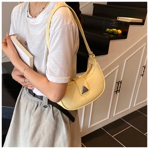 Detail of a creamy yellow half-moon hobo bag featuring crinkle texture and metal logo