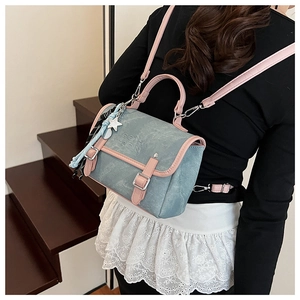 Detail view of a blue and pink dual-strap backpack with metal buckles and star charm