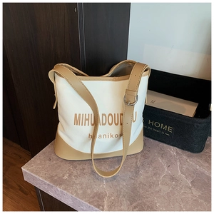 Macro shot of large canvas tote bag with leather trim and brown printed lettering