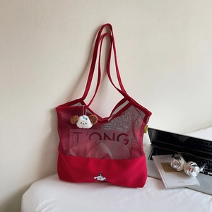 Red mesh and canvas tote bag featuring dog charm and cartoon embroidery on desk